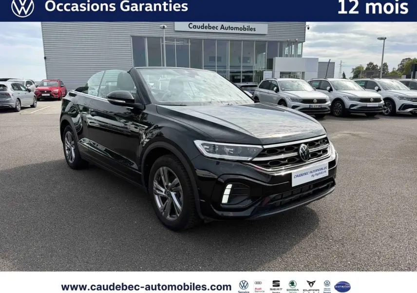 Volkswagen T-Roc Cabriolet noir vue 3/4 avant, toit ouvert, avec jantes alliage et calandre R-Line visible.