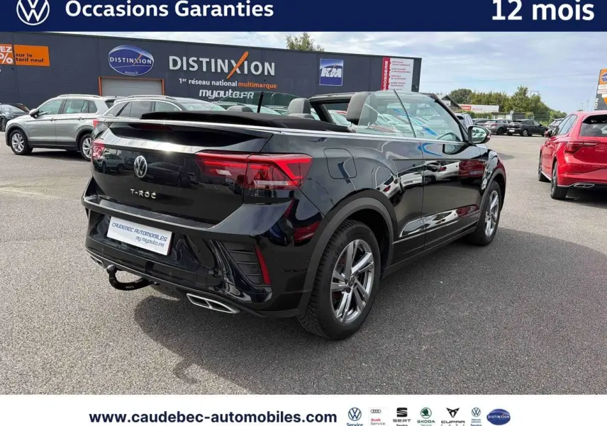 Volkswagen T-Roc Cabriolet noir vue 3/4 arrière droit avec attelage amovible sur parking extérieur.