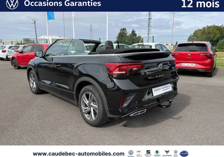 Volkswagen T-Roc Cabriolet noir vu en 3/4 arrière droit, toit ouvert, avec attelage amovible visible.