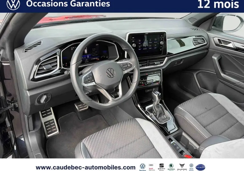 Vue intérieure côté conducteur du Volkswagen T-Roc Cabriolet noir, avec tableau de bord digital et volant multifonction.