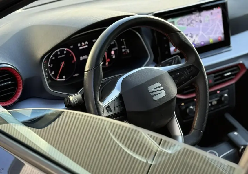 Vue intérieure rapprochée du volant noir et du tableau de bord digital avec écran de navigation d'une SEAT IBIZA 2025.