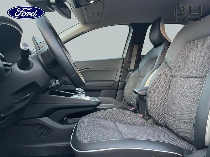 Vue latérale intérieure du Renault Captur 1.6 E-Tech 2021, sièges tissu gris avec surpiqûres blanches et accoudoir central.