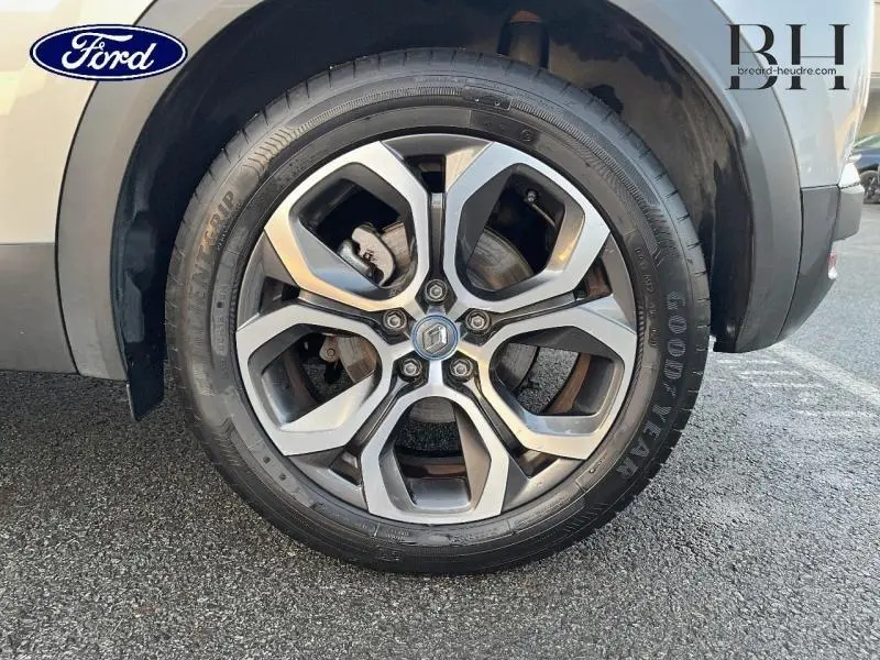 Gros plan sur la jante alliage du Renault Captur gris Highland, montrant le logo Renault au centre.