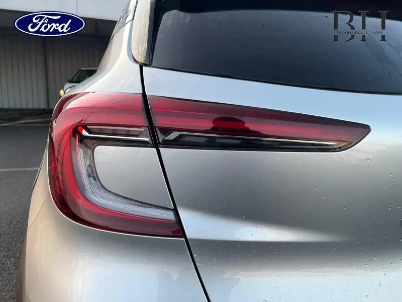 Gros plan sur le feu arrière gauche d'un Renault Captur gris Highland avec détails rouges et noirs, vue arrière.