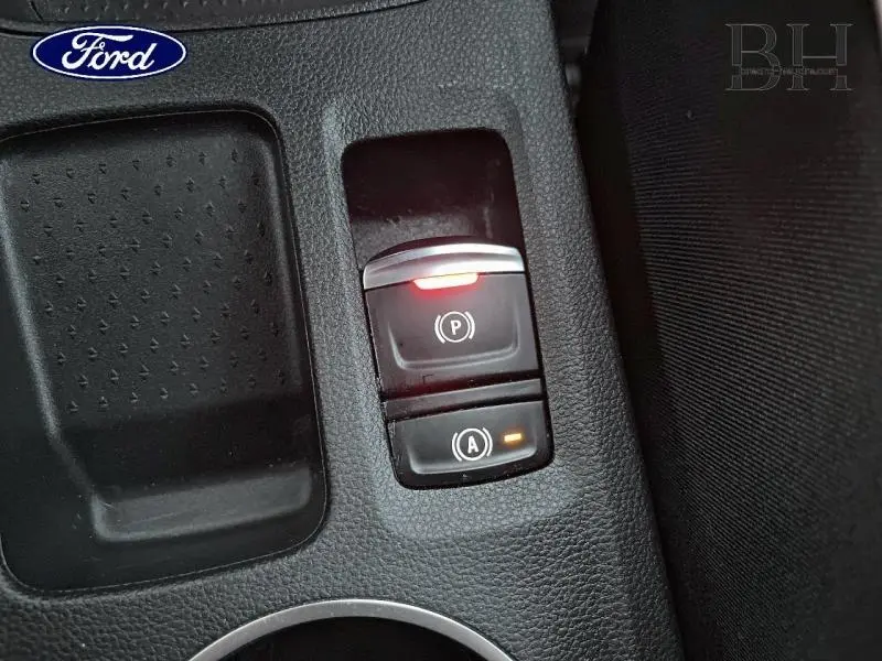 Gros plan sur le bouton de frein de stationnement électrique et arrêt/redémarrage auto dans un Renault Captur gris Highland/Noir Etoile.