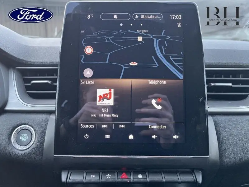 Vue frontale du tableau de bord du Renault Captur gris Highland/Noir Etoile, écran tactile multifonction avec navigation et radio NRJ.