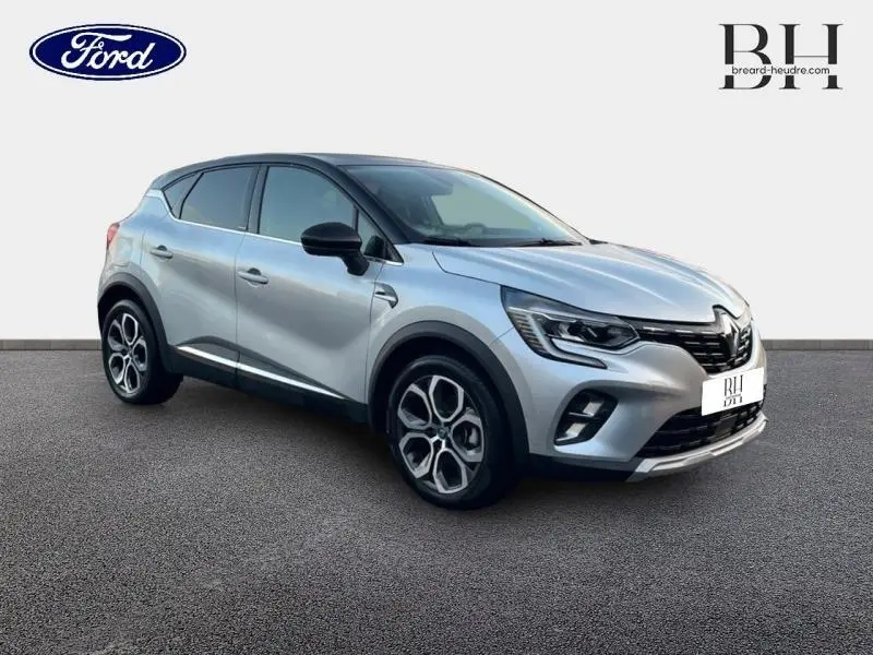 Renault Captur hybride rechargeable gris Highland vue 3/4 avant droit avec toit noir et jantes alu distinctives.