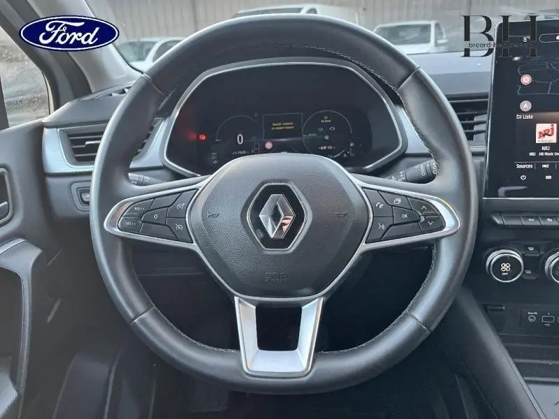 Vue rapprochée du volant noir du Renault Captur 1.6 E-Tech hybride avec commandes multifonctions et tableau de bord numérique.
