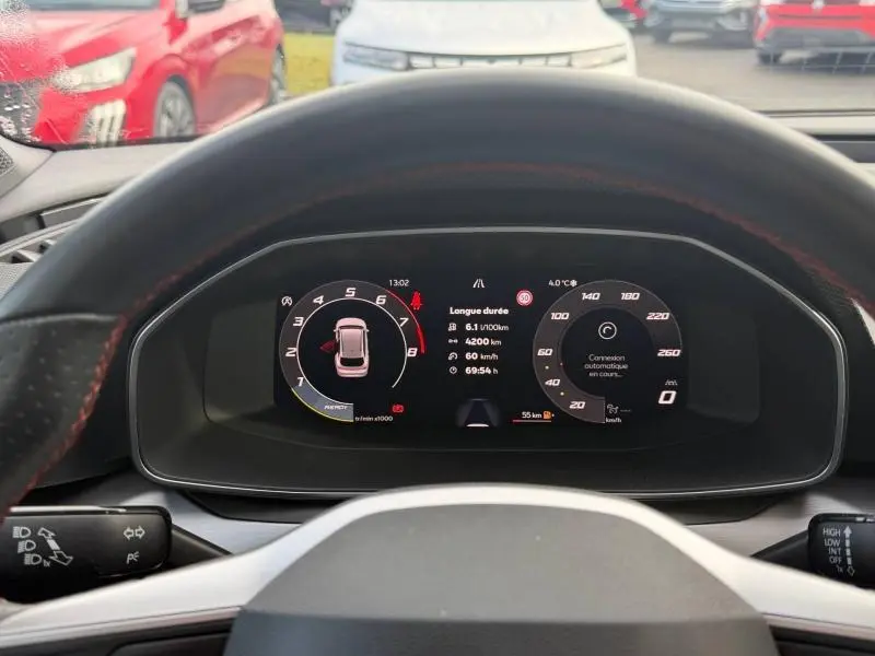 Vue du tableau de bord numérique du SEAT LEON ST 1.5 eTSI Hybrid 2025, affichage clair et moderne derrière le volant.