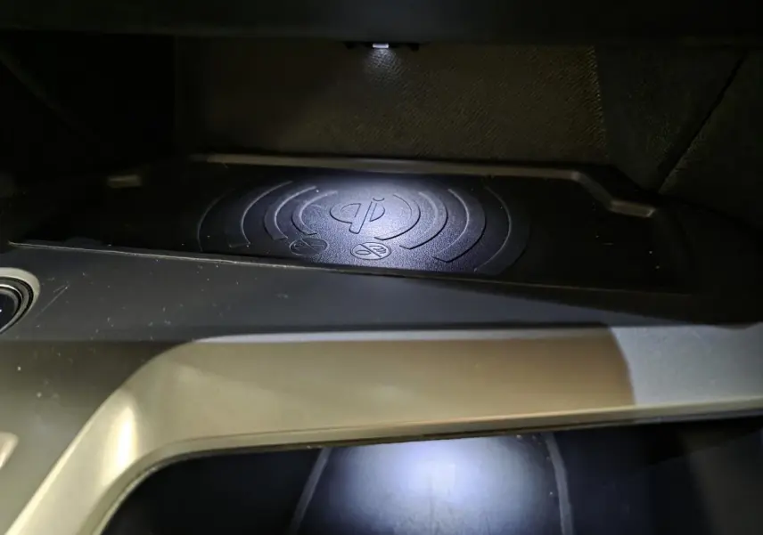 Gros plan sur le chargeur à induction noir intégré dans la console centrale de la Peugeot 308 SW 2024.