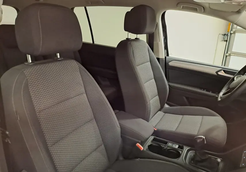 Vue intérieure côté droit montrant les sièges avant en tissu gris foncé du Volkswagen Touran 2025.