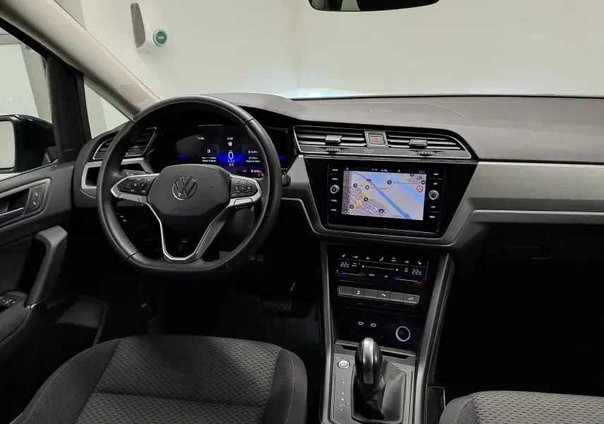 Vue intérieure du tableau de bord du Volkswagen Touran 2025, avec écran tactile et volant multifonction noir.
