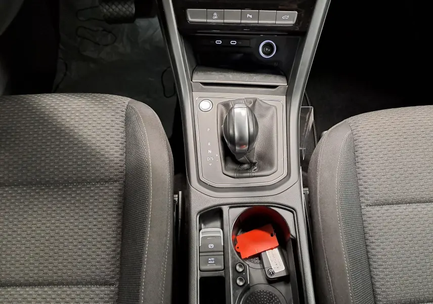 Vue plongeante sur la console centrale du Volkswagen Touran 2025, avec levier de boîte auto et sièges tissu gris.