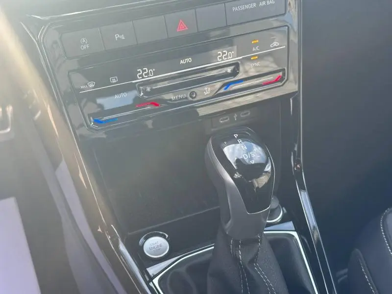 Gros plan sur la console centrale du Volkswagen T-Cross 2025 avec levier de boîte auto DSG7 et commandes climatisation digitales.