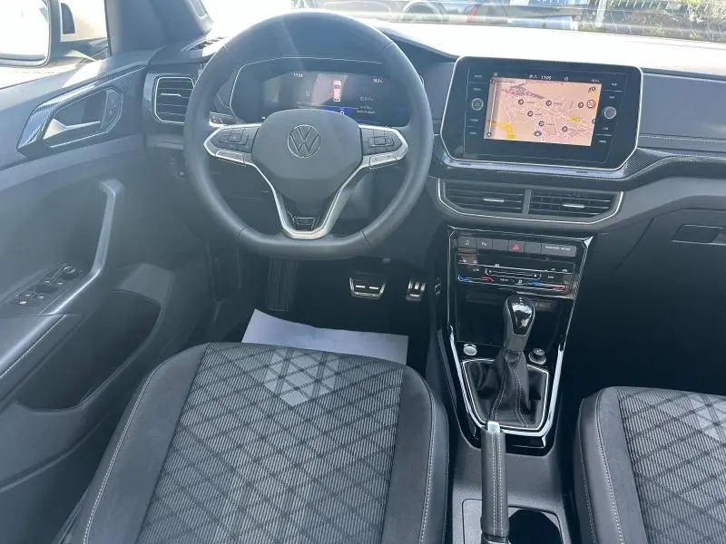 Vue intérieure frontale du Volkswagen T-Cross 2025 essence, tableau de bord avec écran tactile et volant multifonction noir.