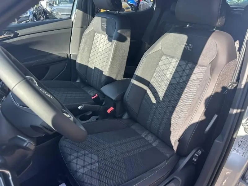 Vue intérieure côté conducteur du Volkswagen T-Cross 2025 R-Line, sièges en tissu noir avec surpiqûres et logo "R".