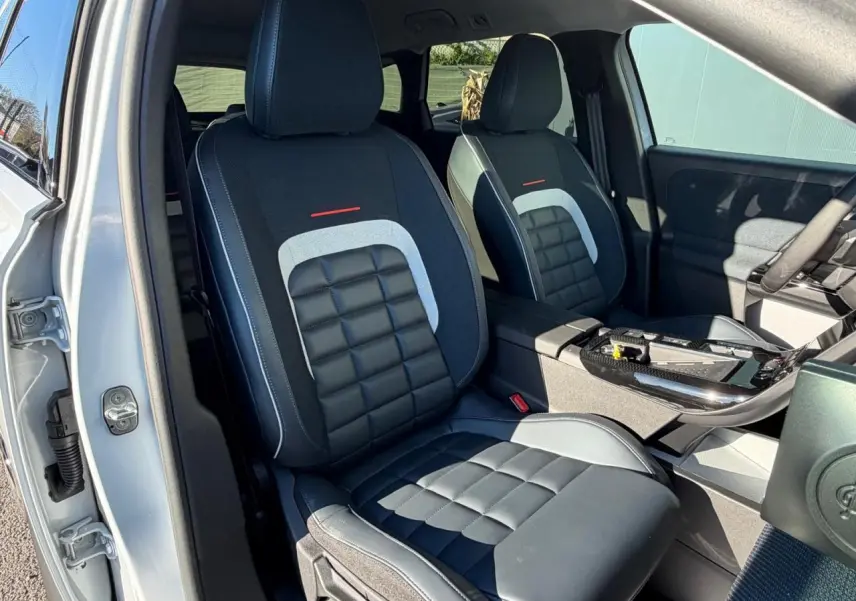 Vue intérieure des sièges avant noirs et gris du Citroën C5 Aircross blanc, avec console centrale et portière côté droit visibles.