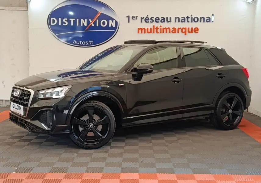 Audi Q2 35 TFSI S Line noir vue de profil côté gauche dans un showroom avec jantes noires distinctives.