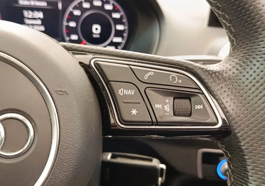 Gros plan sur le volant perforé noir de l’Audi Q2 35 TFSI avec commandes vocales et navigation intégrées.