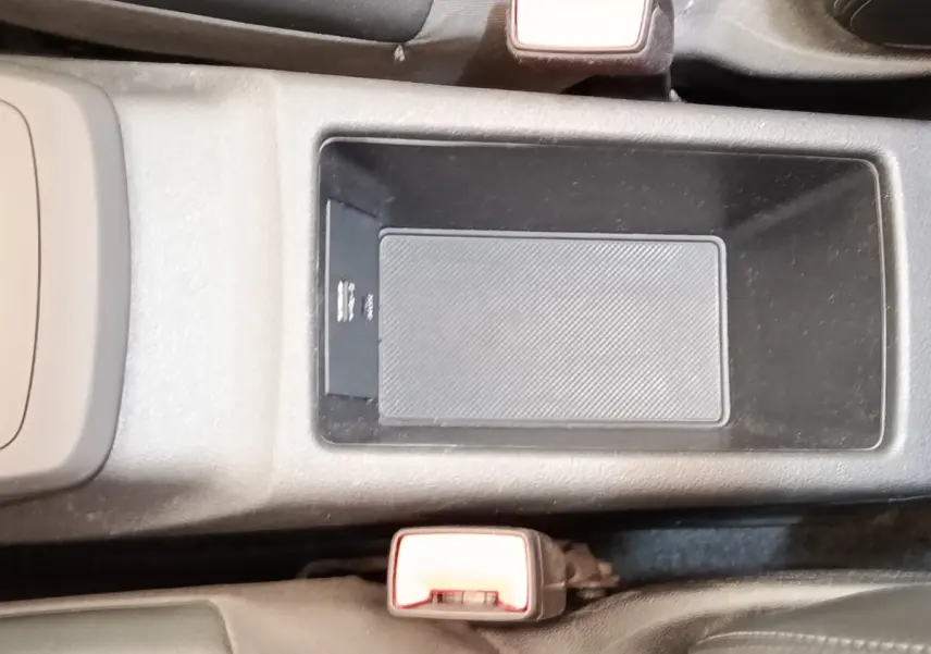 Vue rapprochée de la console centrale noire de l’Audi Q2 35 TFSI 150 S Tronic S Line avec rangement et boucle de ceinture rouge.