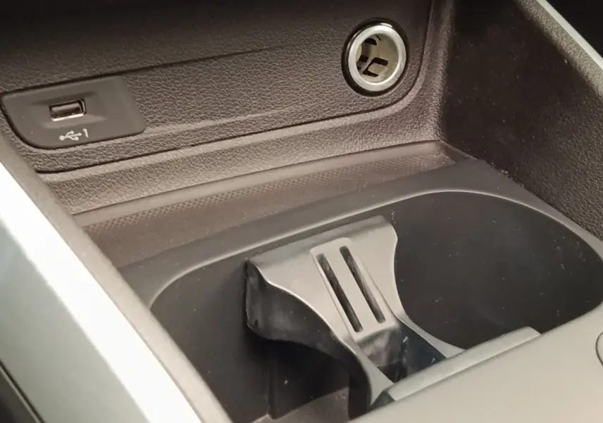 Gros plan sur la console centrale noire de l’Audi Q2, montrant un port USB et un porte-gobelets intégré.
