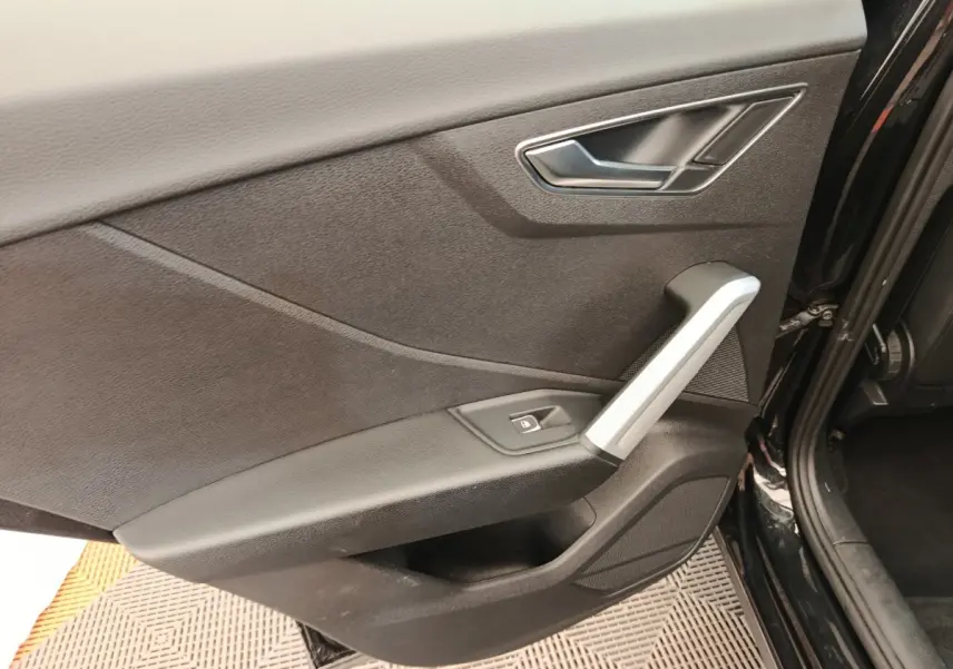 Gros plan sur la porte arrière droite noire de l'Audi Q2 35 TFSI 150 S Line avec poignée argentée et bouton de verrouillage.