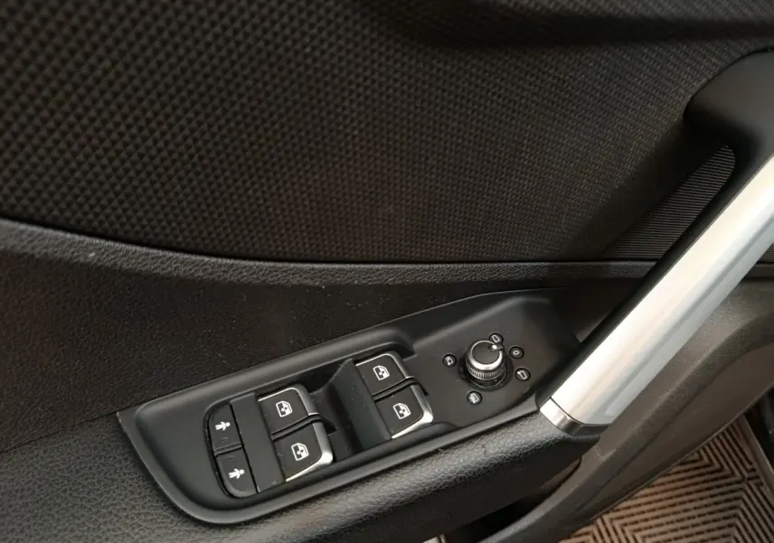 Gros plan sur les commandes des vitres et rétroviseurs côté conducteur de l'Audi Q2 noir, intérieur porte avant.