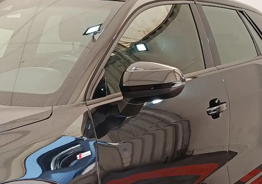 Vue latérale côté gauche d'un Audi Q2 noir 35 TFSI S Line avec logo S sur l'aile avant et rétroviseur noir brillant.