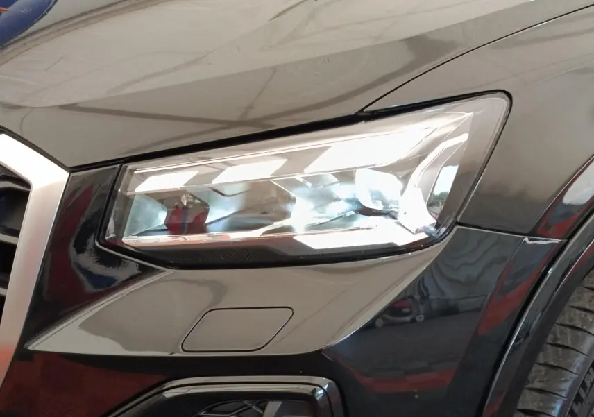 Gros plan sur le phare avant droit noir brillant de l'Audi Q2 35 TFSI 150 S Tronic S Line 2021.