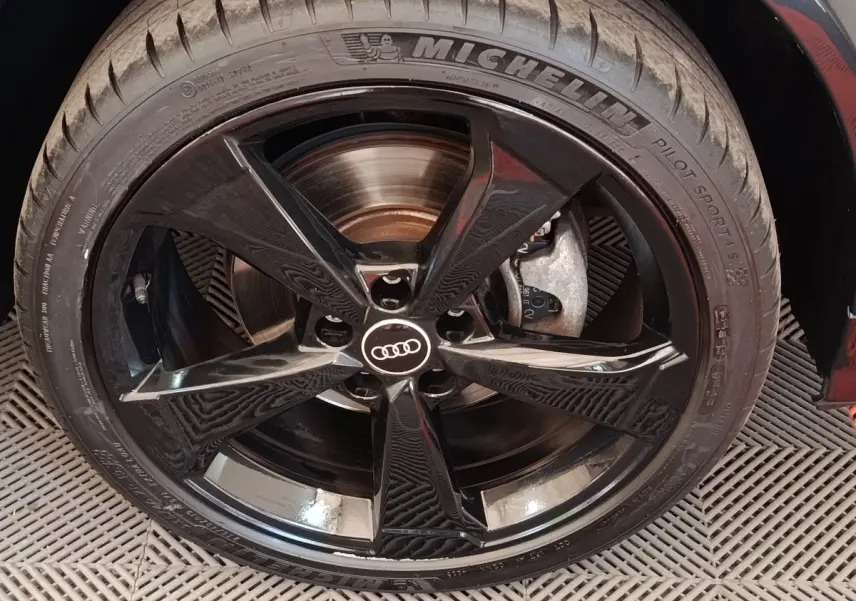 Gros plan sur la jante noire brillante Audi à 5 branches du SUV Q2 35 TFSI S Line, pneu Michelin visible.