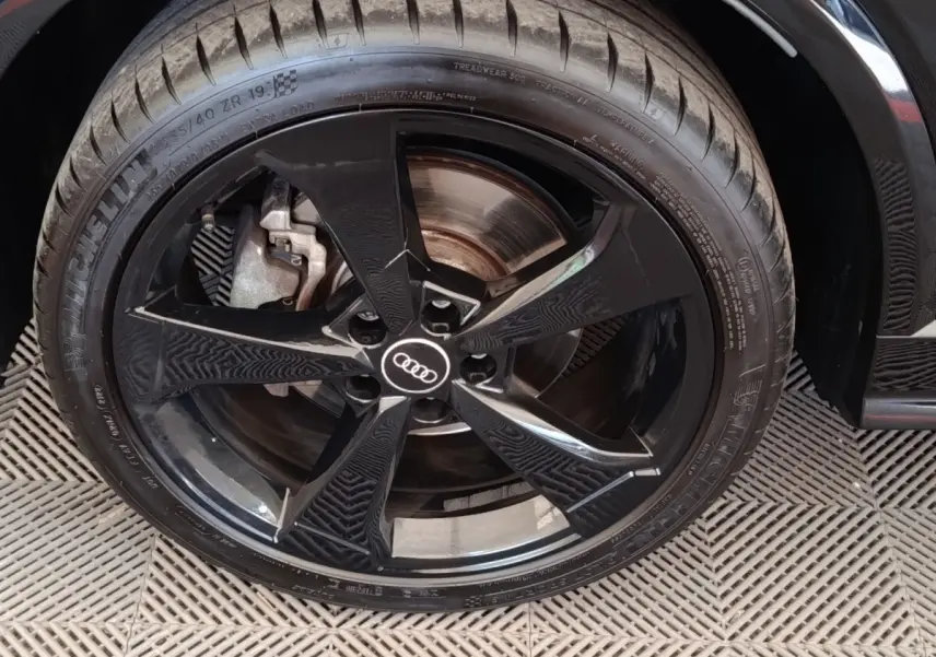 Gros plan sur la roue avant droite noire d’un Audi Q2 35 TFSI S Line, avec jante en alliage noir brillant.