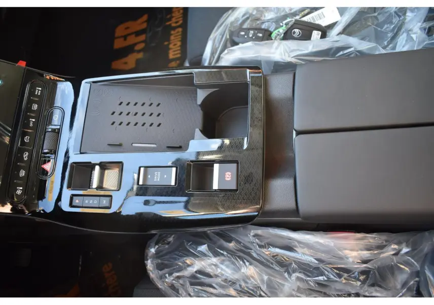 Vue rapprochée de la console centrale noire brillante du Citroën C5 Aircross hybride avec commandes de boîte auto et accoudoir.