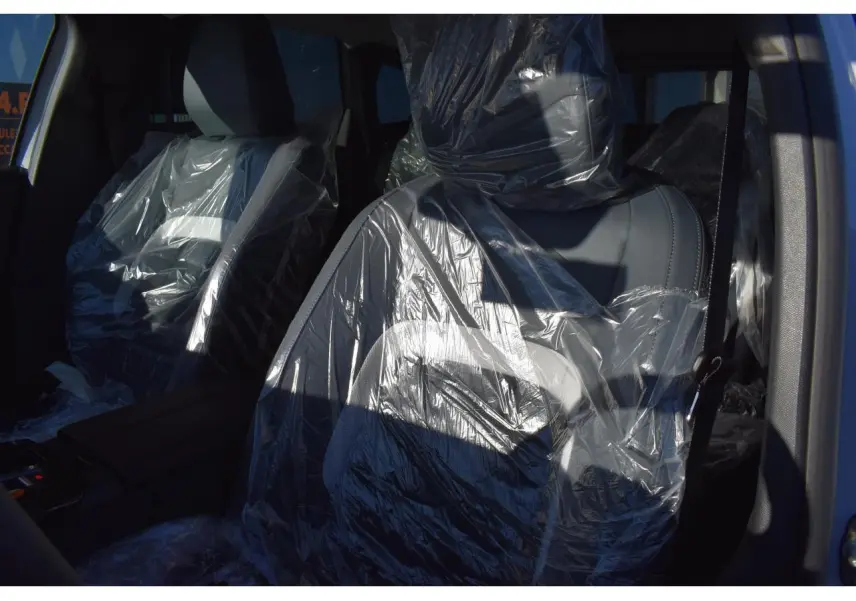 Vue intérieure rapprochée des sièges avant protégés par des housses plastiques dans un Citroën C5 Aircross blanc.