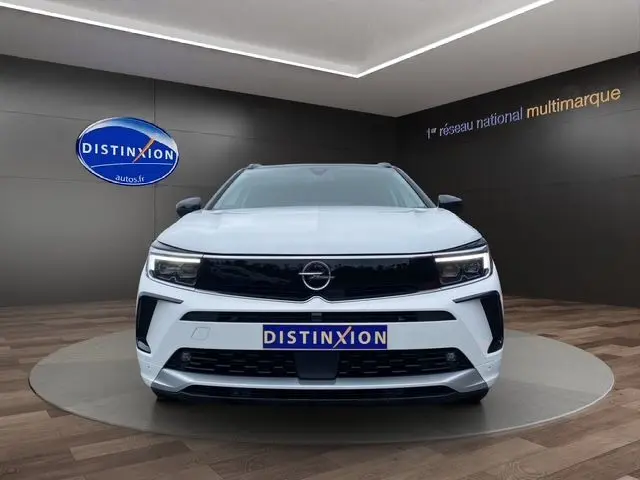 Vue frontale d'un Opel Grandland 2024 blanc Arktis avec toit noir, calandre noire et phares Matrix LED allumés.