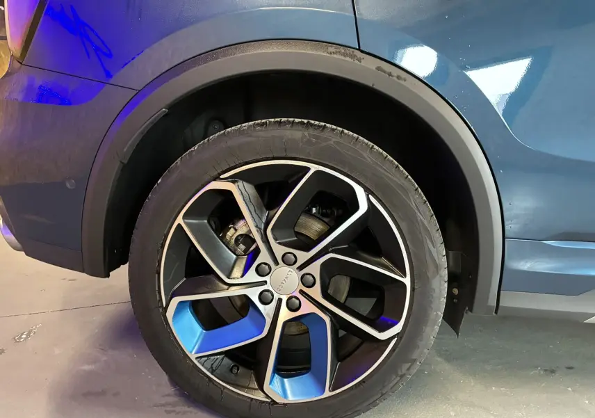 Gros plan sur la roue arrière droite bleu et noir du SUV Lynk & Co 01 hybride rechargeable 2023.