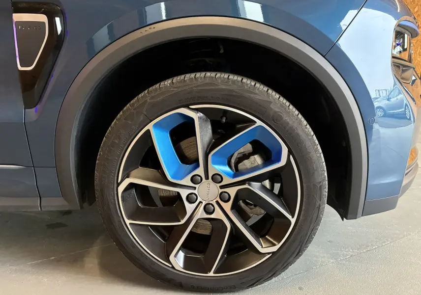 Gros plan sur la roue avant droite bleu et noir du SUV Lynk & Co 01 hybride rechargeable 2023 avec jante design bicolore.