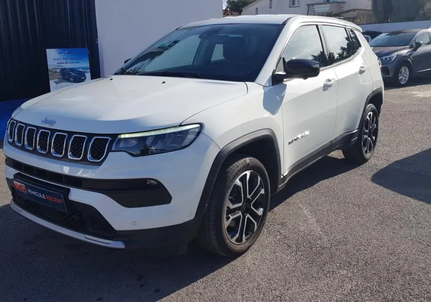 Jeep Compass blanc vu en 3/4 avant droit, avec jantes alliage noires et calandre distinctive à sept fentes.