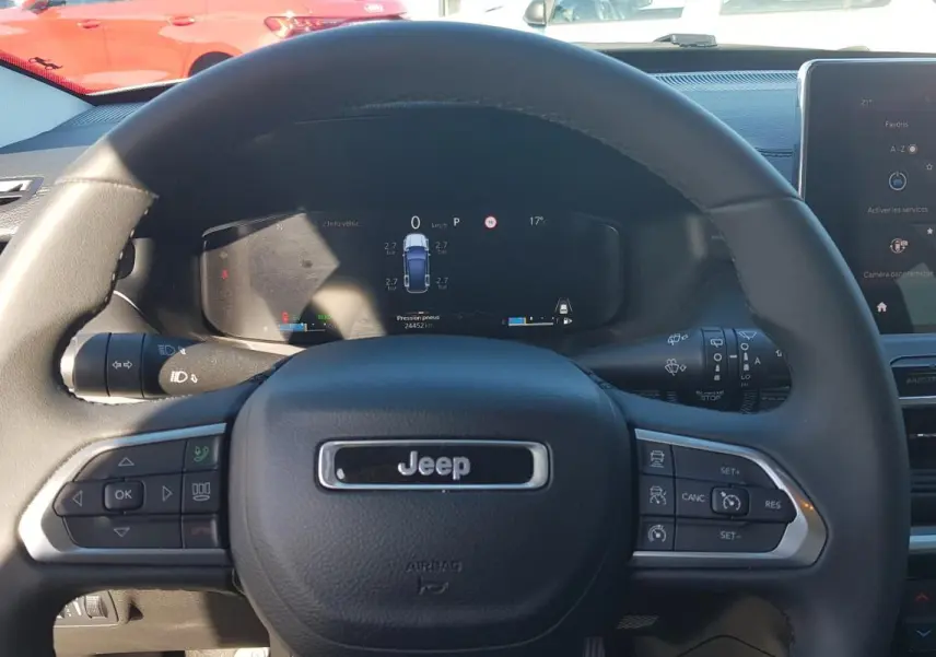 Vue centrée sur le volant noir du Jeep Compass 2024 avec tableau de bord numérique et écran tactile à droite.