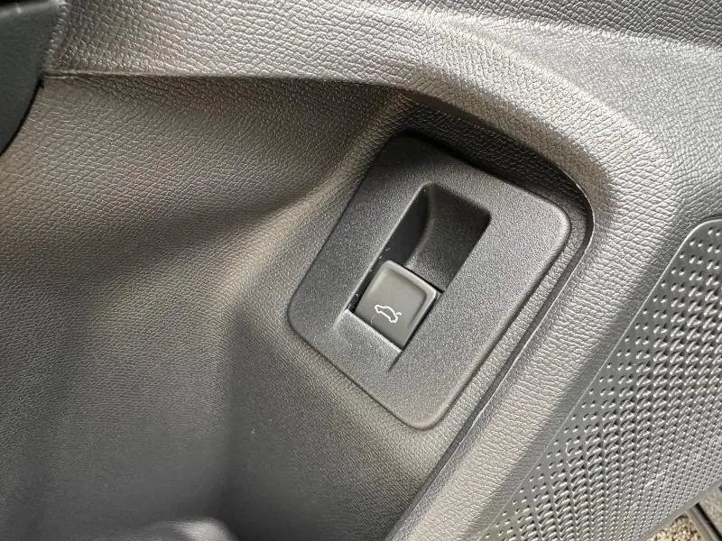 Bouton d'ouverture du coffre en plastique noir sur panneau intérieur gris graphite du CUPRA Formentor 2.0 TDI 150ch V DSG7.