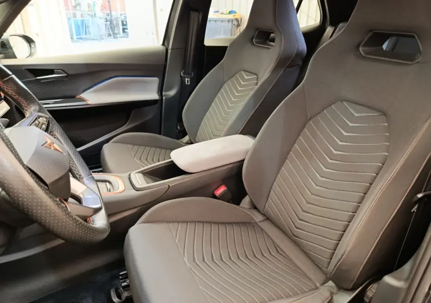 Vue intérieure côté conducteur de la CUPRA BORN 230ch gris foncé, avec sièges sport et volant cuir multifonctions.