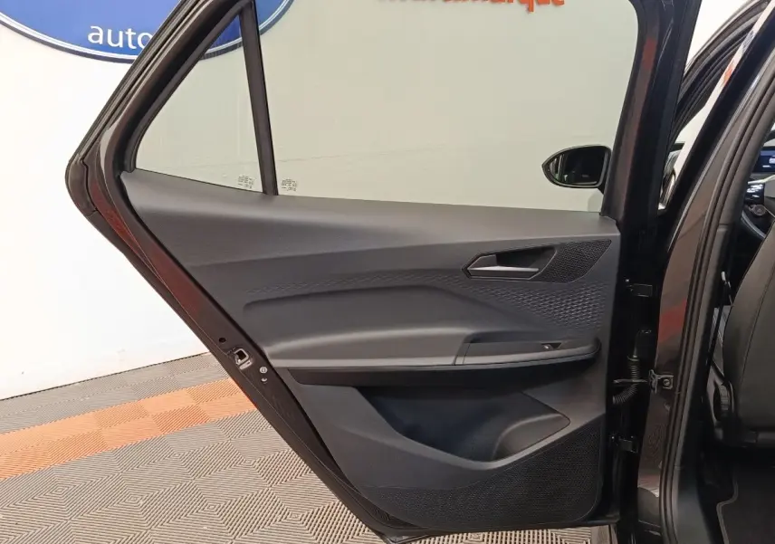 Vue intérieure de la porte arrière gauche gris foncé du CUPRA BORN 230ch avec détails des commandes et haut-parleur intégré.