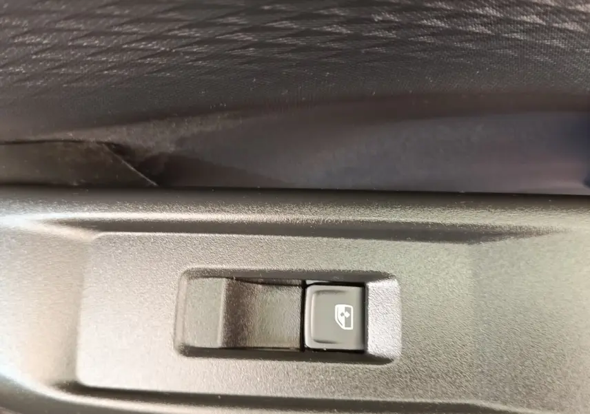 Gros plan sur le bouton de commande de lève-vitre électrique, intérieur noir du côté gauche du CUPRA Born gris foncé.