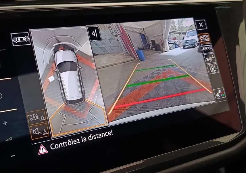 Écran tactile intérieur montrant la caméra 360° et vue arrière du Volkswagen Tiguan blanc en stationnement.