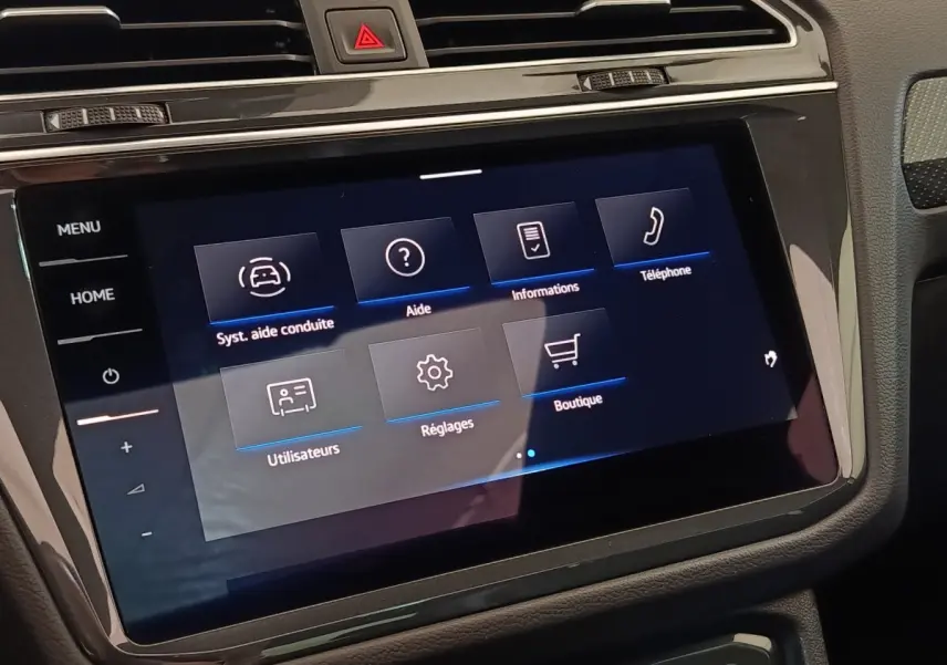 Écran tactile central du tableau de bord du Volkswagen Tiguan blanc, affichant le menu des aides à la conduite.