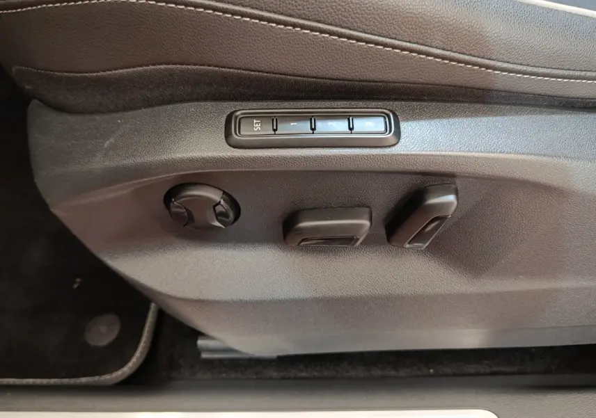 Réglages électriques des sièges côté conducteur du Volkswagen Tiguan blanc, avec boutons de mémoire de position.