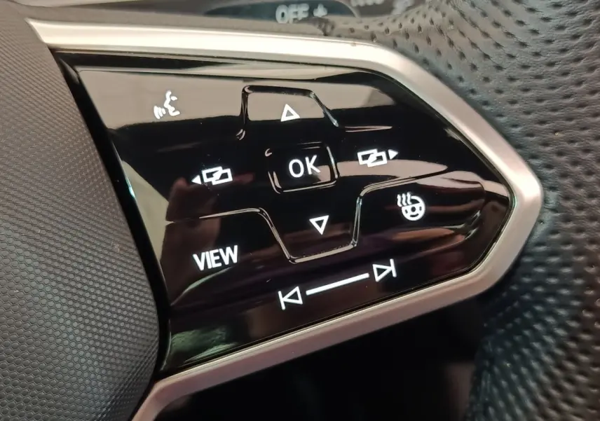 Gros plan sur les commandes multifonctions noires du volant cuir du Volkswagen Tiguan blanc 2023 hybride rechargeable.
