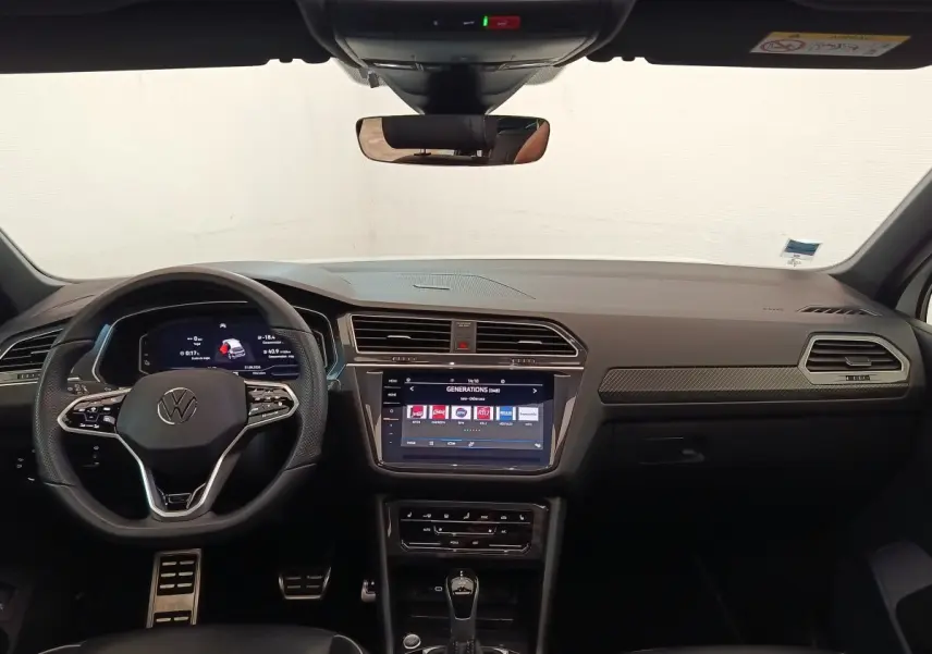 Vue intérieure frontale du tableau de bord noir du Volkswagen Tiguan 1.4 eHybrid 2023 avec écran tactile central et volant multifonctions.