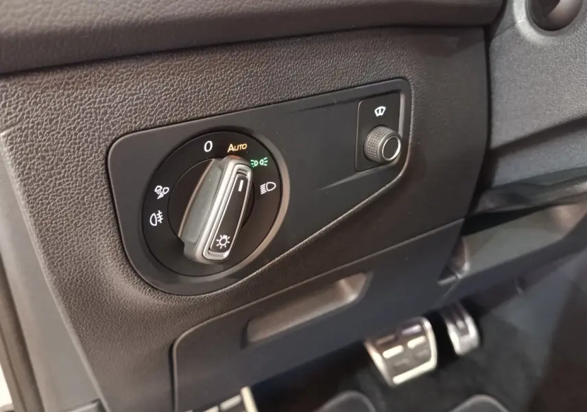 Détail du tableau de bord côté gauche du Volkswagen Tiguan blanc 2023, avec commande des phares et réglage du lave-glace.