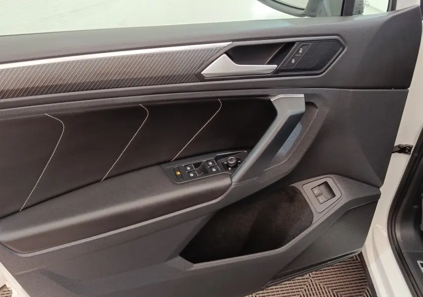 Vue intérieure côté gauche de la porte avant blanche du Volkswagen Tiguan 1.4 eHybrid avec garniture noire et surpiqûres blanches.