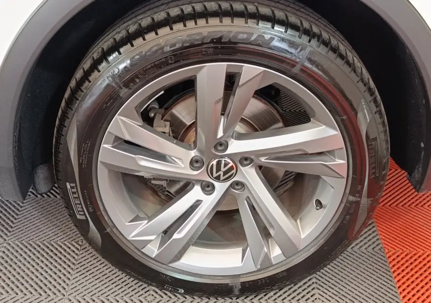 Gros plan sur la roue avant droite du Volkswagen Tiguan blanc, jante alliage 5 branches doubles et pneu Pirelli Scorpion.